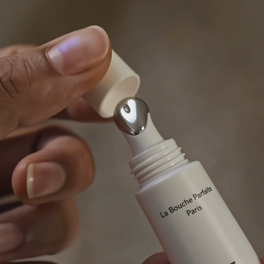 Woman applying the Lip Balm Corrector N°3 with its rounded metal tip on her lower lip, The Essential 5 lip care set by La Bouche Parfaite